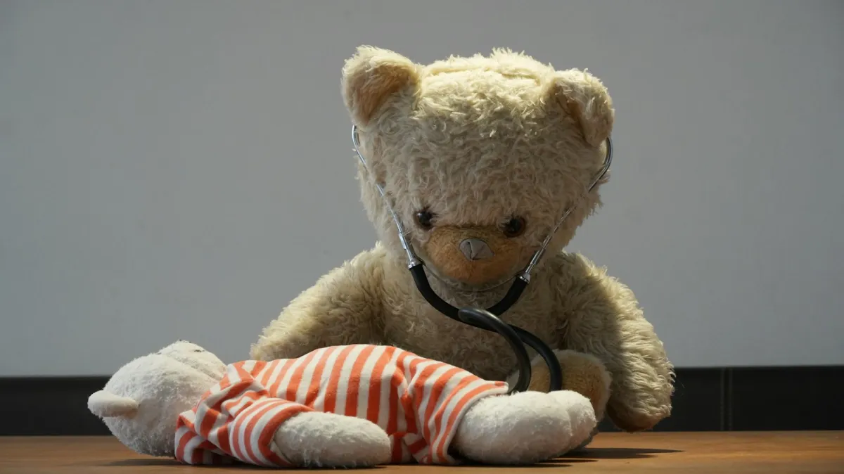 A teddy bear wearing a stethoscope checking a smaller toy bear in striped pyjamas A teddy bear wearing a stethoscope checking a smaller toy bear in striped pyjamas