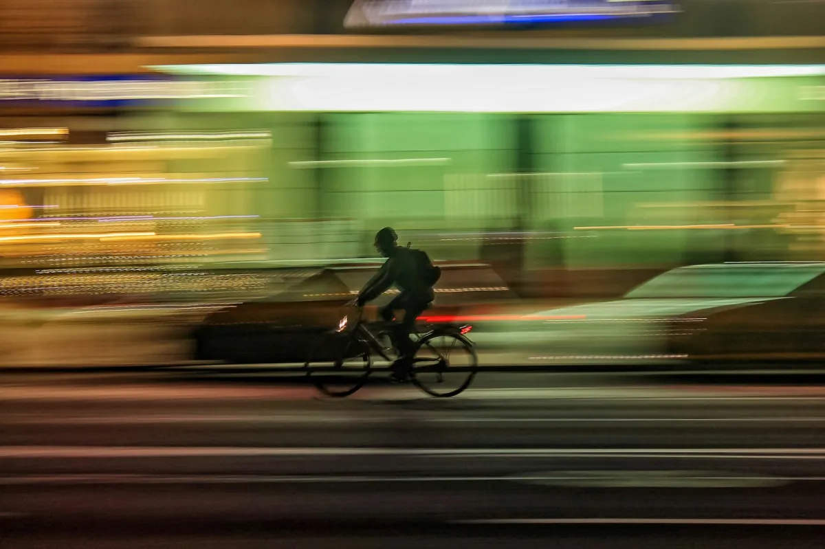 Motion-blurred cyclist riding along a city street at night Motion-blurred cyclist riding along a city street at night