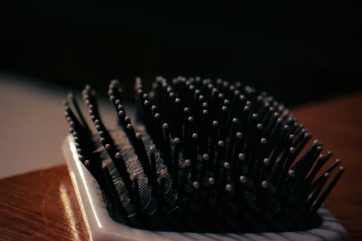 Close-up of a paddle hairbrush resting on a wooden table