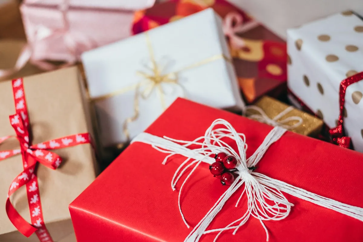 Pile of wrapped Christmas presents with red and white ribbons