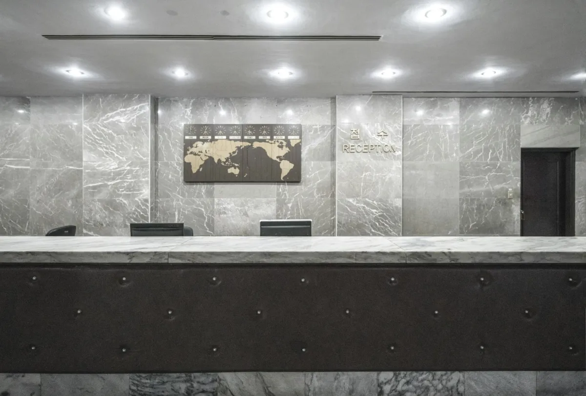 An empty office reception desk in front of a marble wall with a world map An empty office reception desk in front of a marble wall with a world map