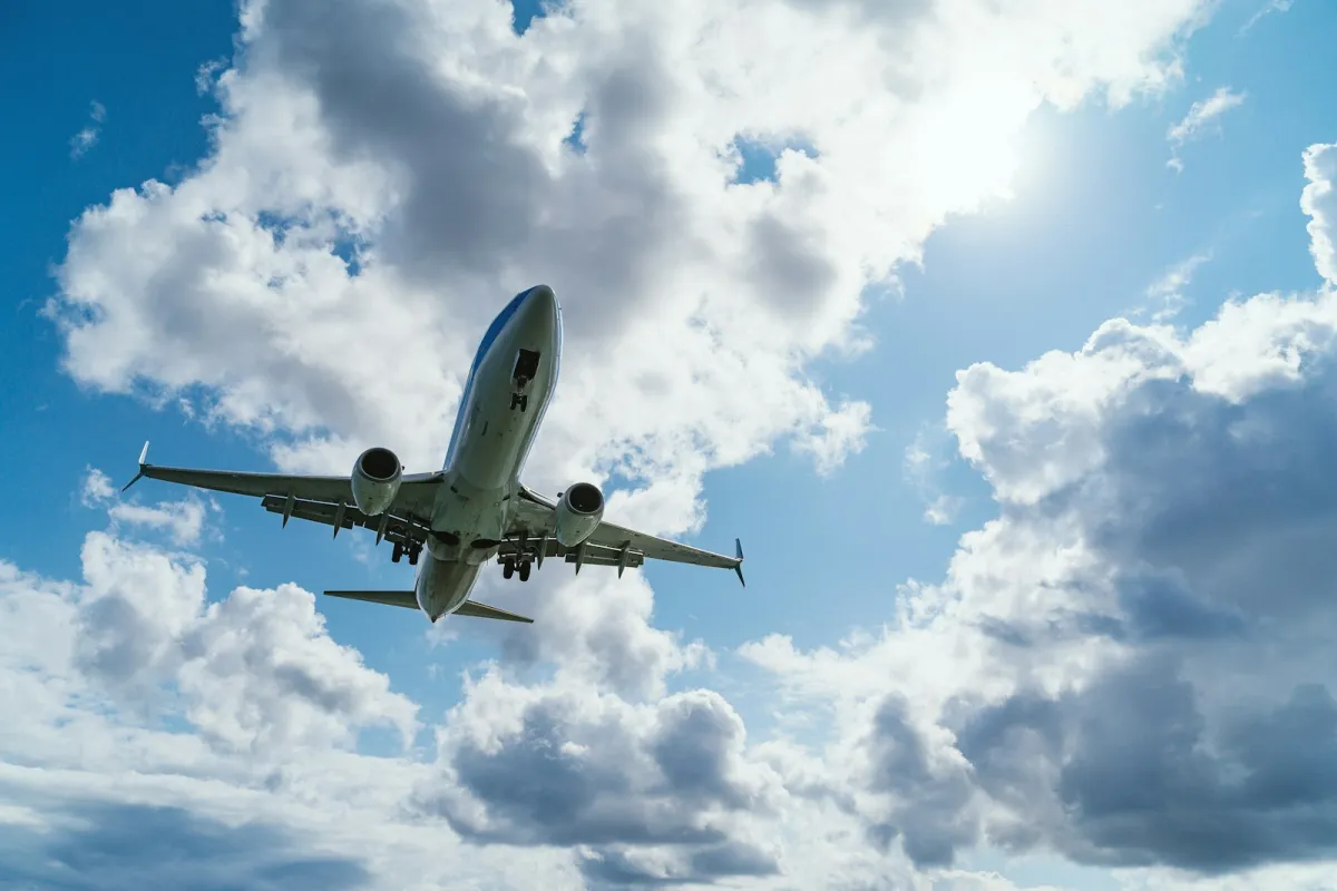A passenger jet seen from below as it flies through a blue sky with white clouds A passenger jet seen from below as it flies through a blue sky with white clouds