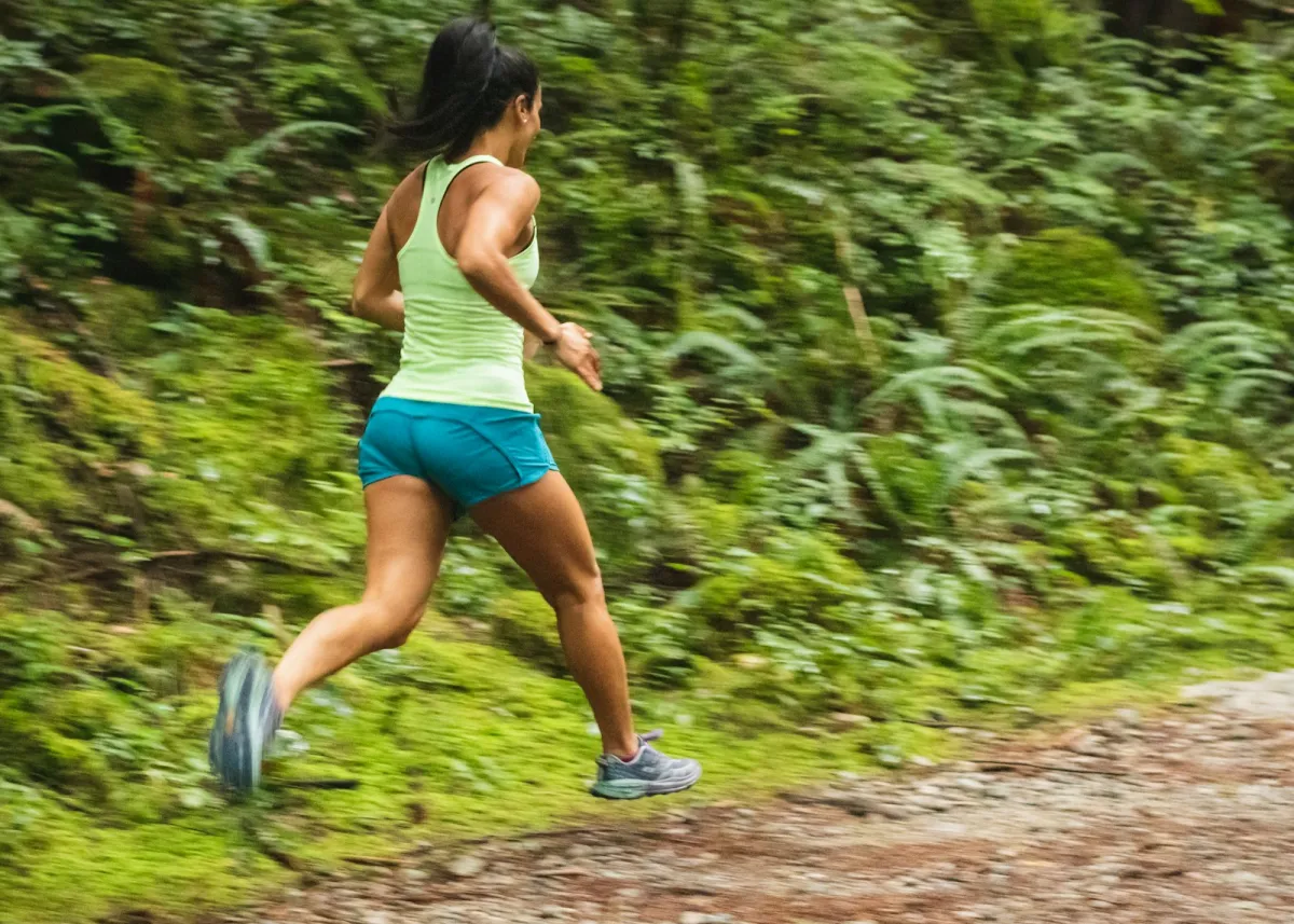 Runner on a woodland trail lined with ferns