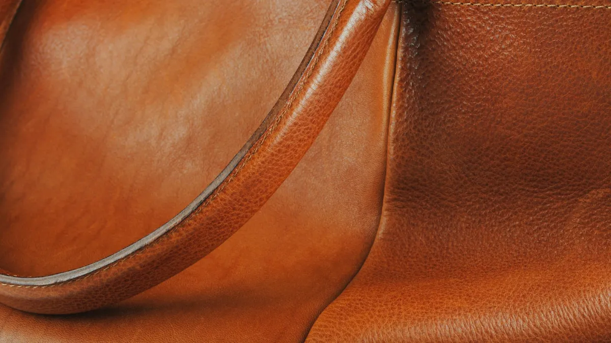 Close-up of a tan leather handbag showing the grain and stitched handle
