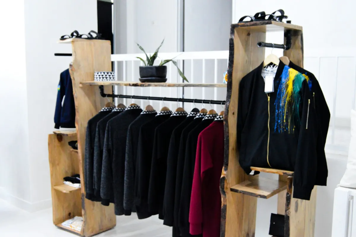 Jackets and jumpers hanging on a wooden clothes rail in a bright shop Jackets and jumpers hanging on a wooden clothes rail in a bright shop