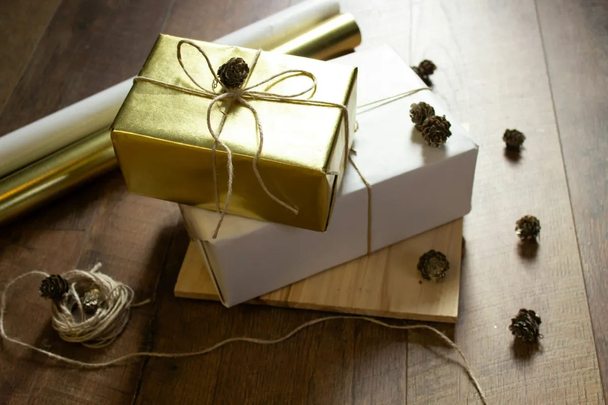 Gold and white wrapped gifts tied with twine and pine cones