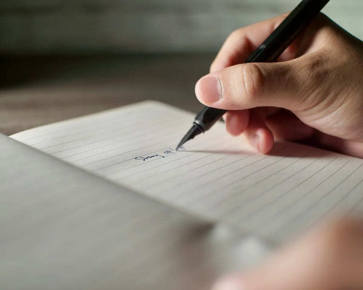 A hand writing notes with a fountain pen in a lined notebook