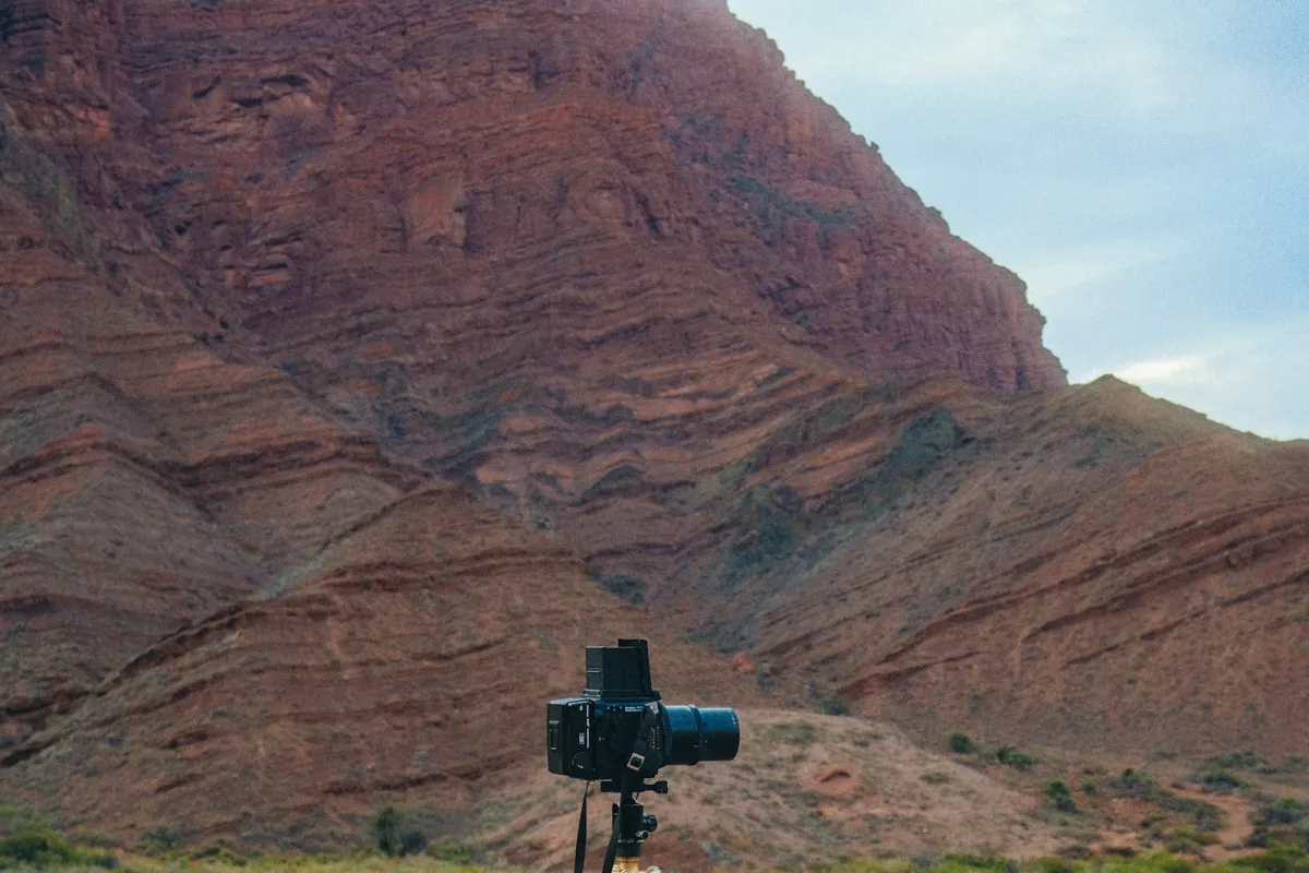A medium-format camera on a tripod in front of a red rock mountain