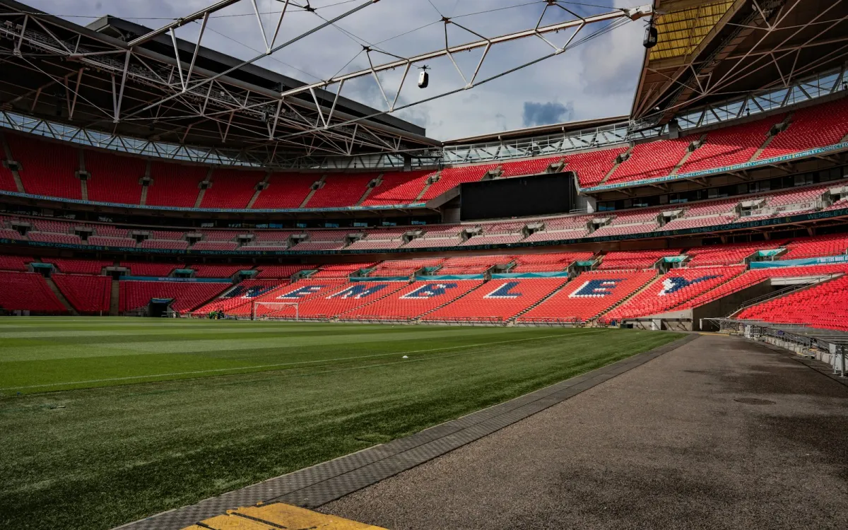 Rows of empty red seats around the pitch of a large football stadium Rows of empty red seats around the pitch of a large football stadium