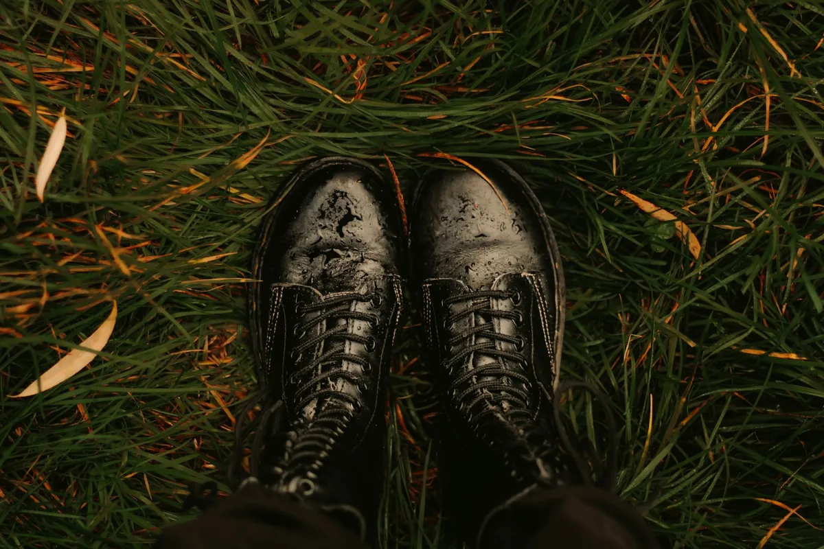 Pair of black lace-up boots standing in wet grass