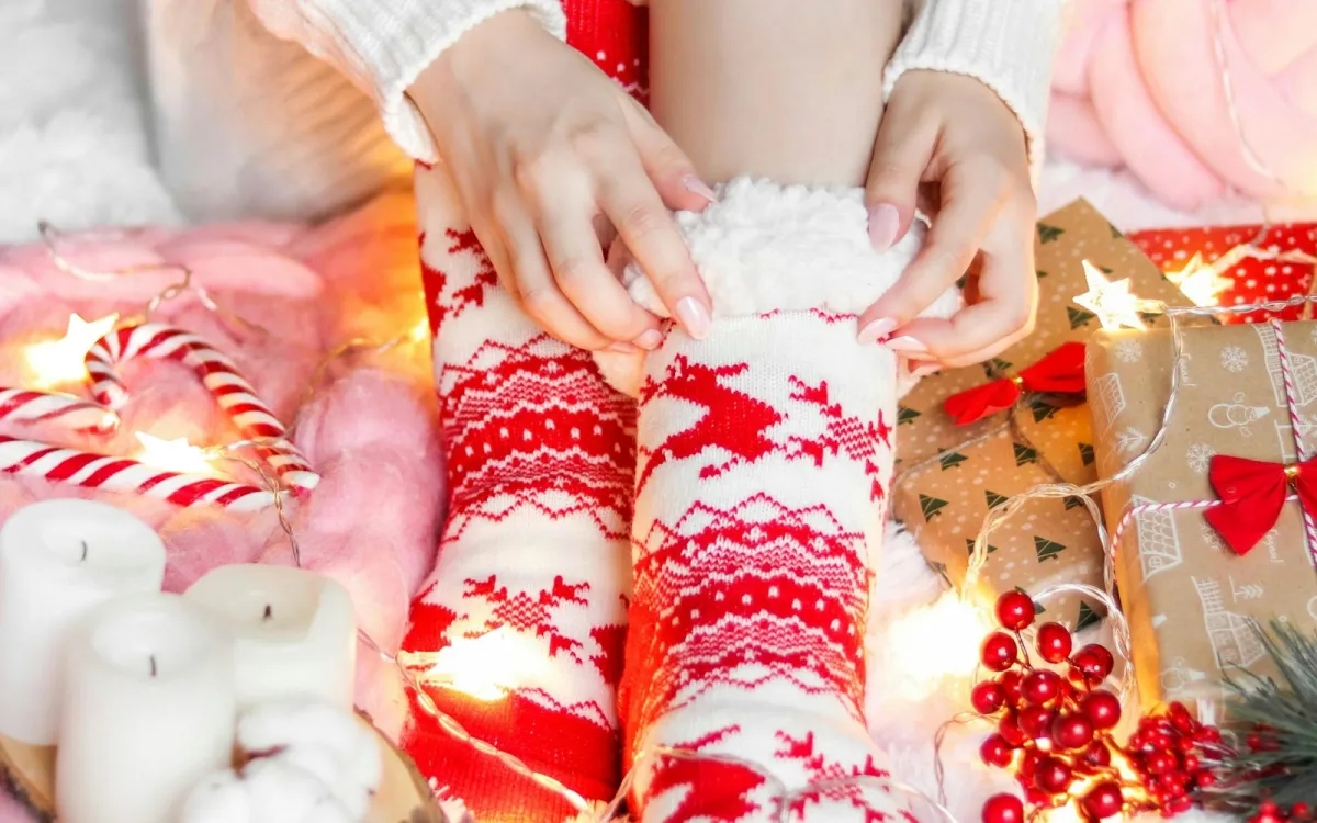 Cosy red and white Christmas socks surrounded by fairy lights, candy canes and wrapped presents Cosy red and white Christmas socks surrounded by fairy lights, candy canes and wrapped presents