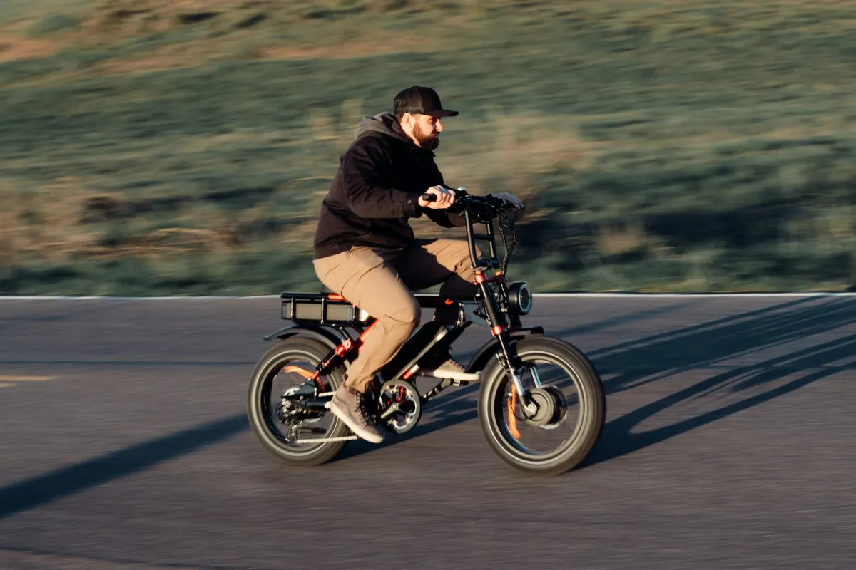 A rider on a fat-tyre electric bike on an open road at sunset
