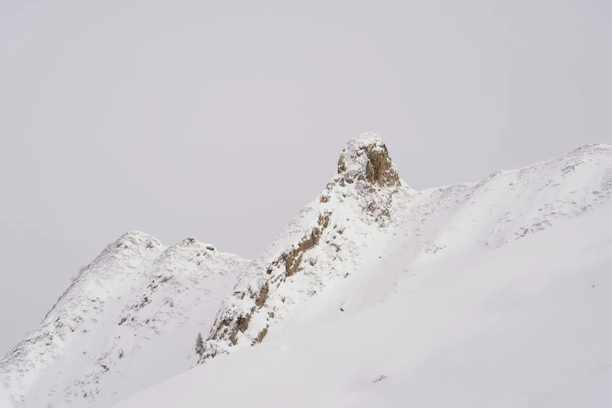 A snow-covered rocky mountain ridge under a pale winter sky A snow-covered rocky mountain ridge under a pale winter sky