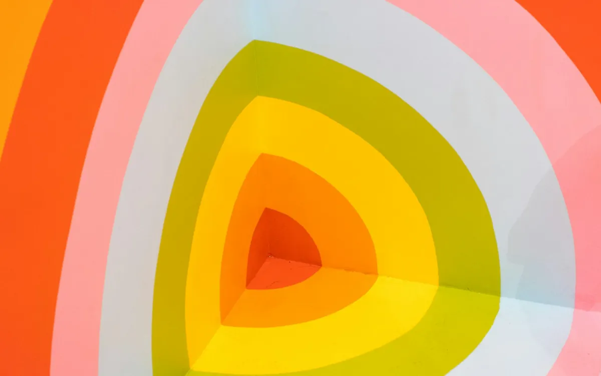Bold orange, yellow and pink stripes painted across the corner of a wall Bold orange, yellow and pink stripes painted across the corner of a wall