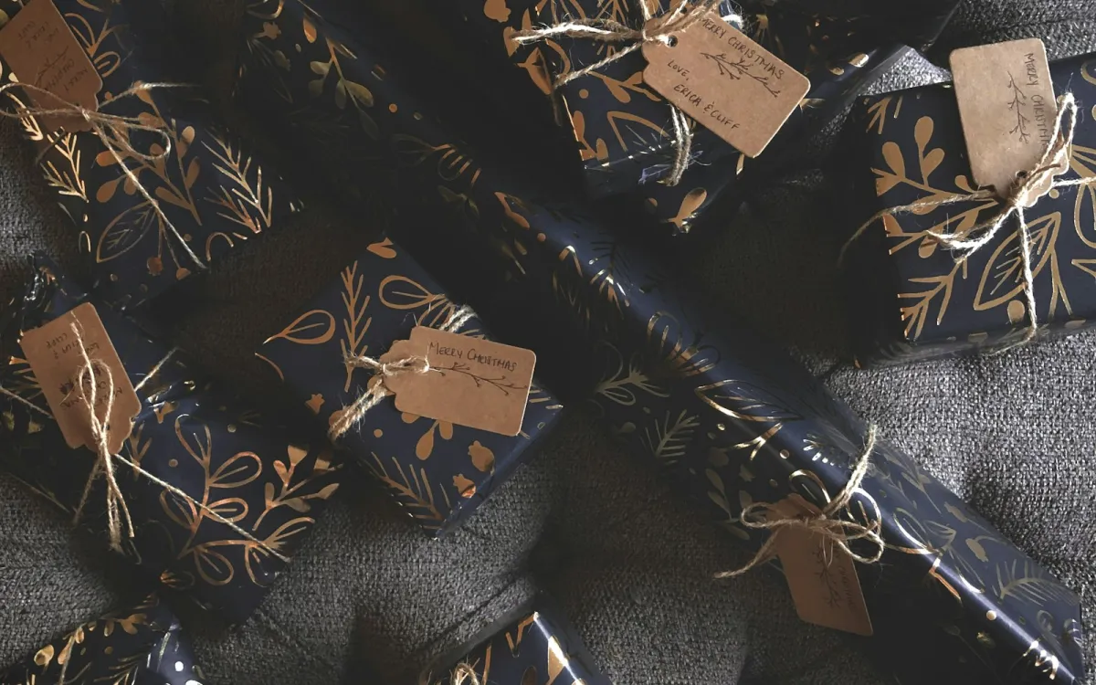 Presents in navy and gold wrapping paper tied with twine and handwritten Christmas tags Presents in navy and gold wrapping paper tied with twine and handwritten Christmas tags