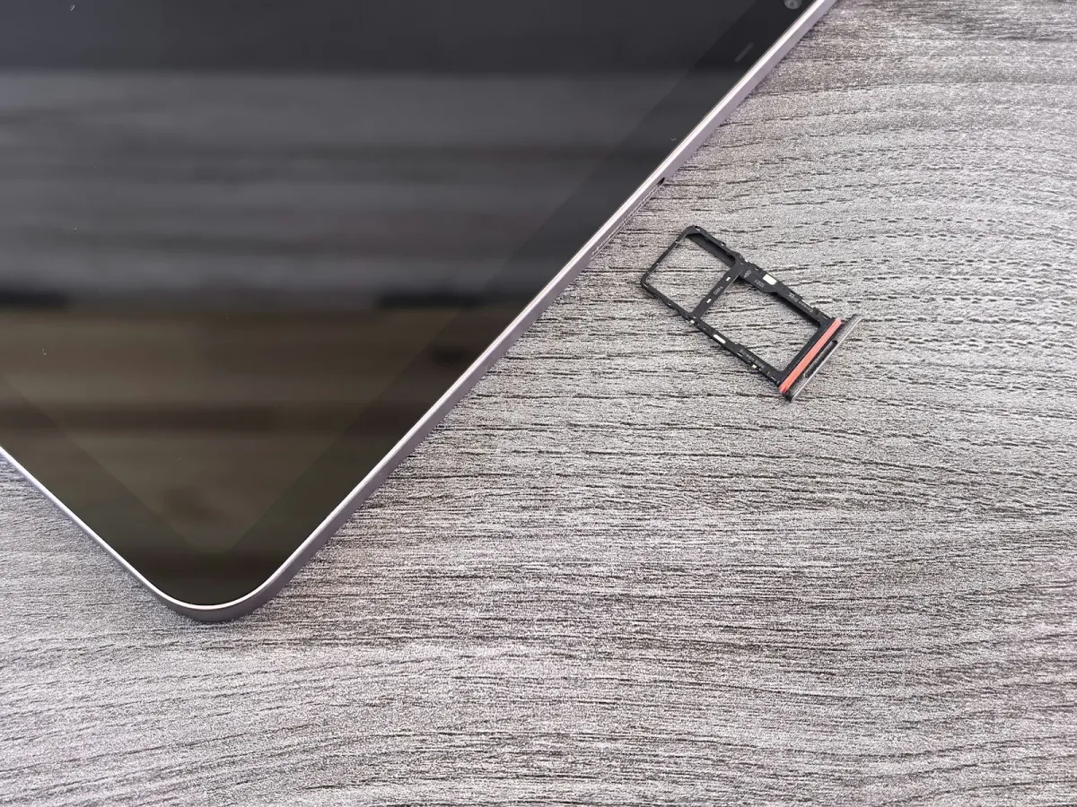 Smartphone on a wooden desk with its SIM card tray removed beside it Smartphone on a wooden desk with its SIM card tray removed beside it