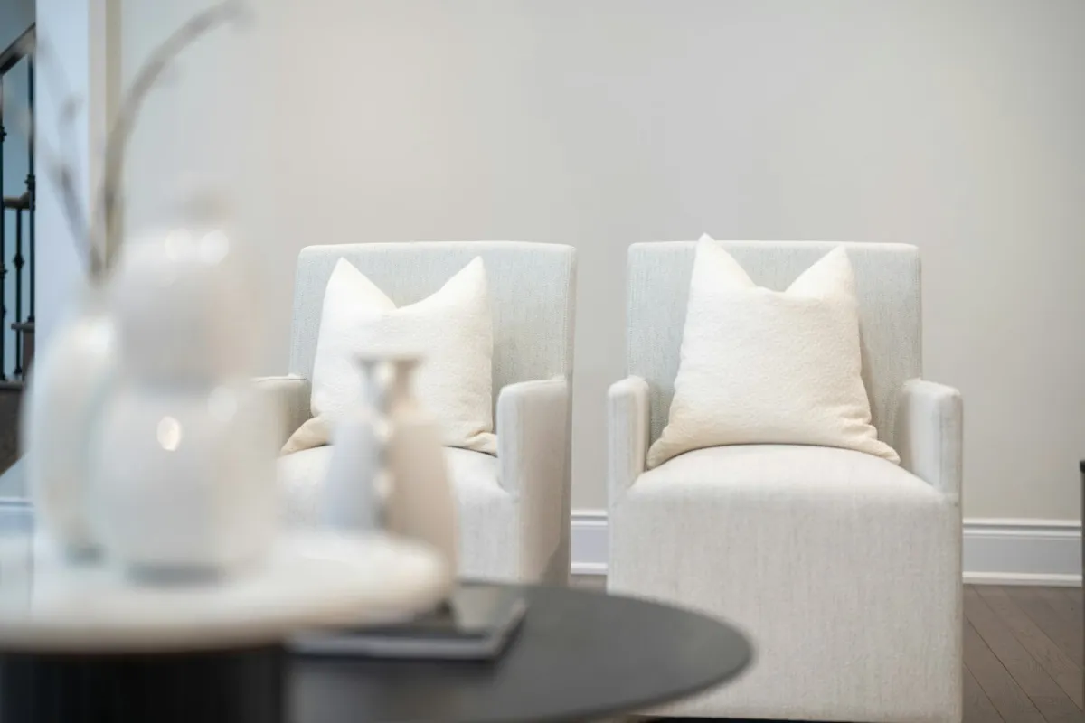 Two white armchairs with cushions in a calm, softly lit room