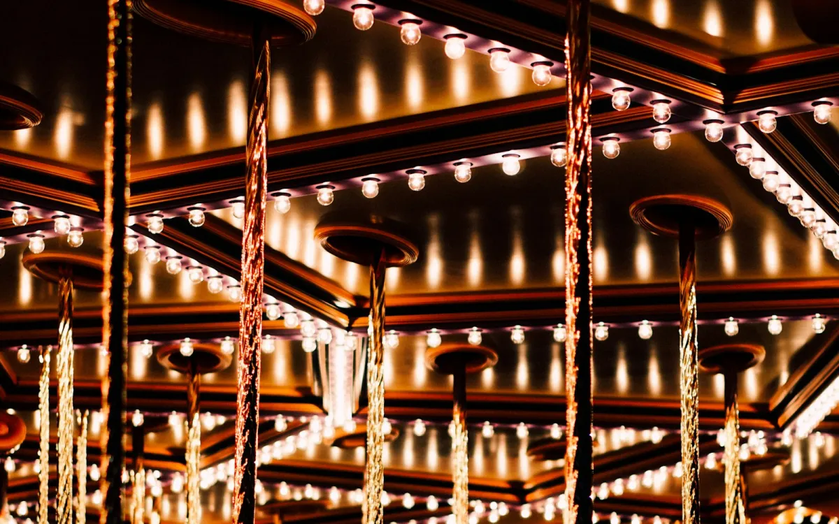 Rows of warm light bulbs and twisted brass poles on a carousel canopy at night Rows of warm light bulbs and twisted brass poles on a carousel canopy at night