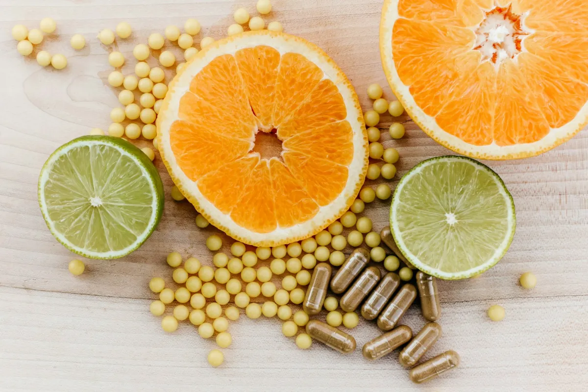 Citrus slices with supplement capsules and soft gels on a wooden surface