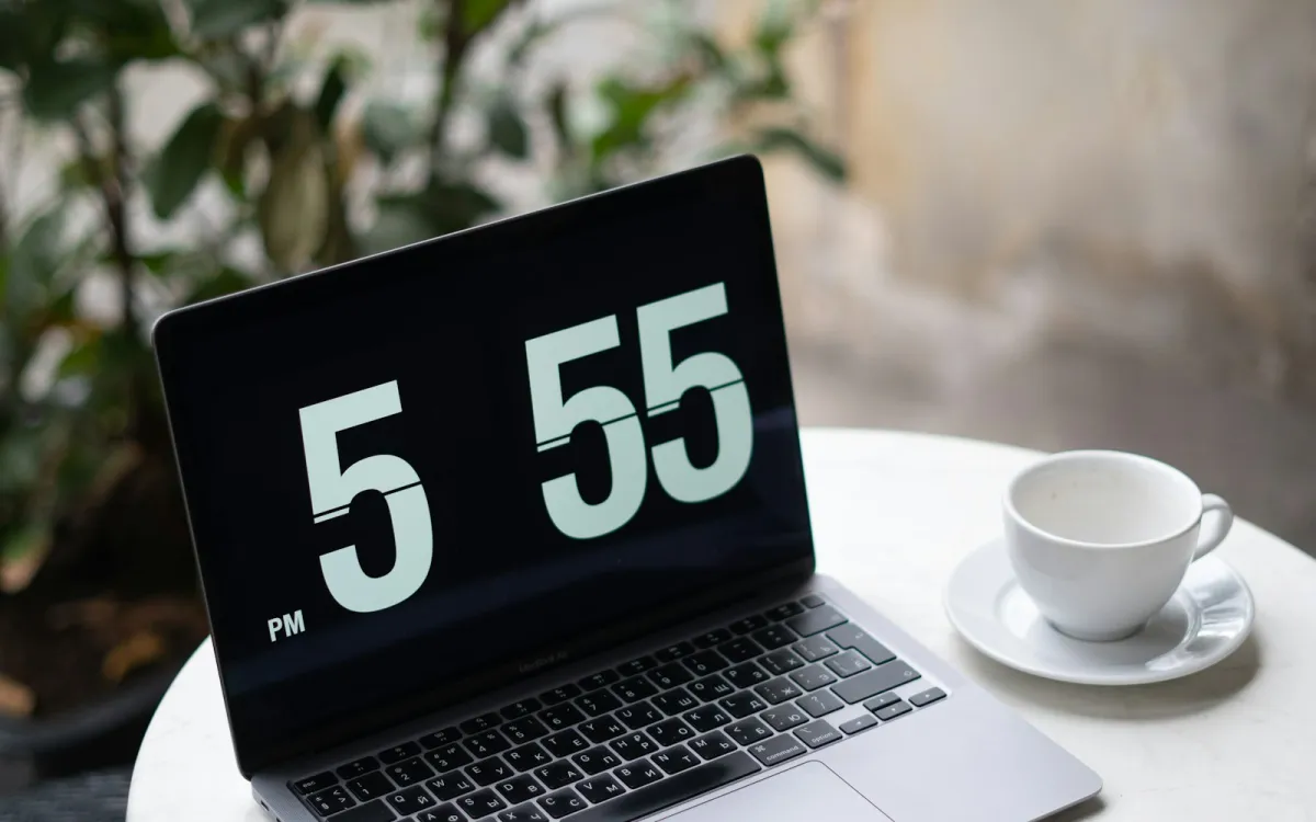 A laptop and an empty coffee cup on a round café table