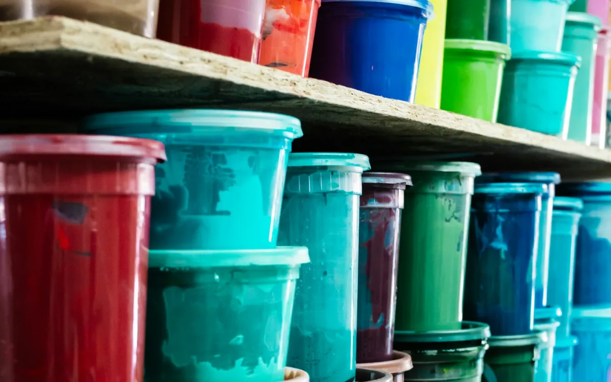 Shelves stacked with red, teal, blue and green paint tubs