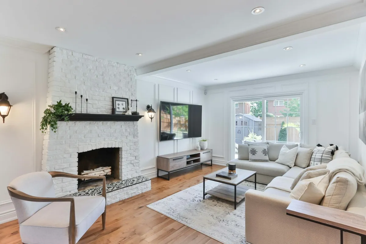 Bright living room with a wall-mounted flat-screen TV, white brick fireplace and grey corner sofa