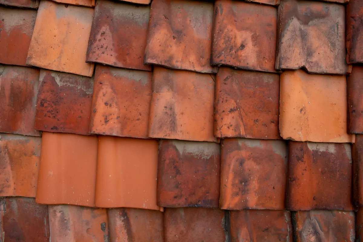 Close-up of weathered clay roof tiles with a few newer replacement tiles Close-up of weathered clay roof tiles with a few newer replacement tiles