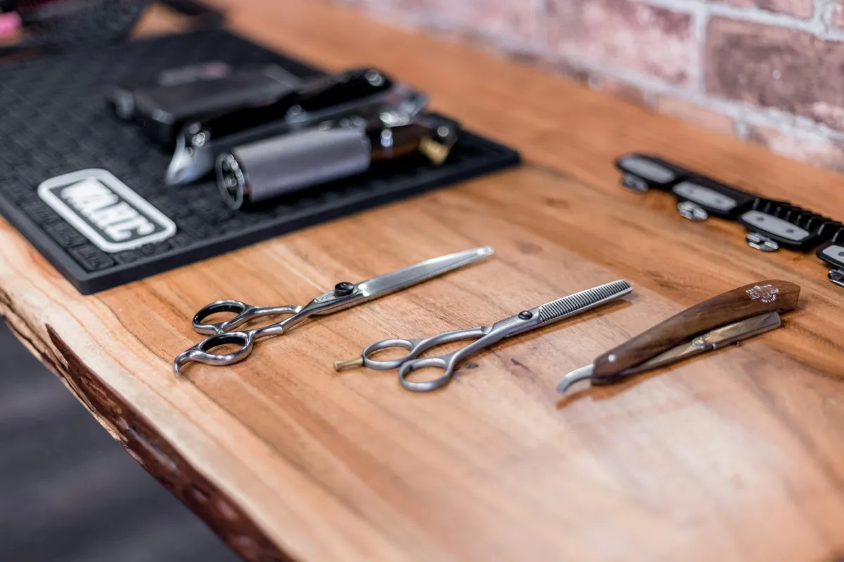 Barber's scissors, thinning shears and a straight razor laid out on a wooden counter Barber's scissors, thinning shears and a straight razor laid out on a wooden counter