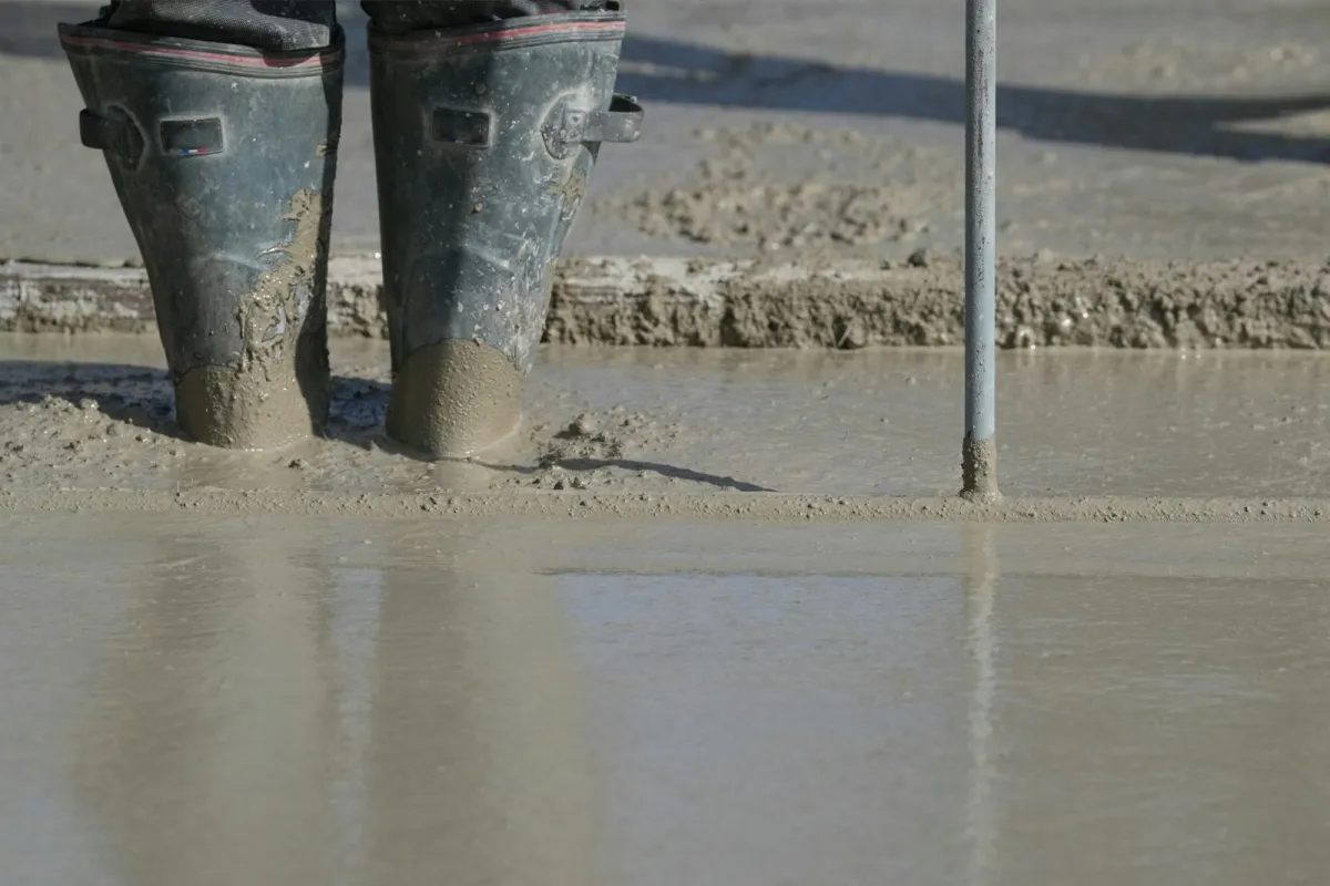 A worker's boots standing in freshly poured concrete on a building site A worker's boots standing in freshly poured concrete on a building site