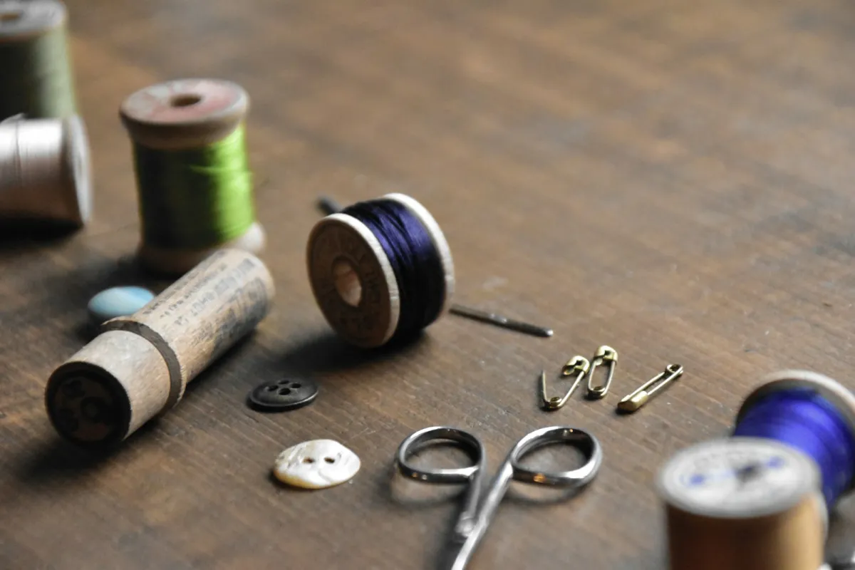 Wooden thread spools, buttons, safety pins and small scissors on a wooden table
