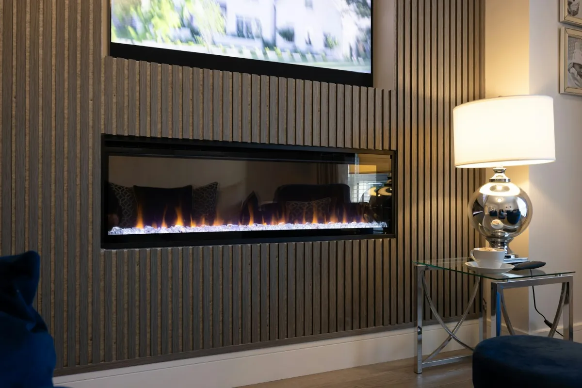 A living room with slatted wall panelling around an inset fire and white skirting along the floor
