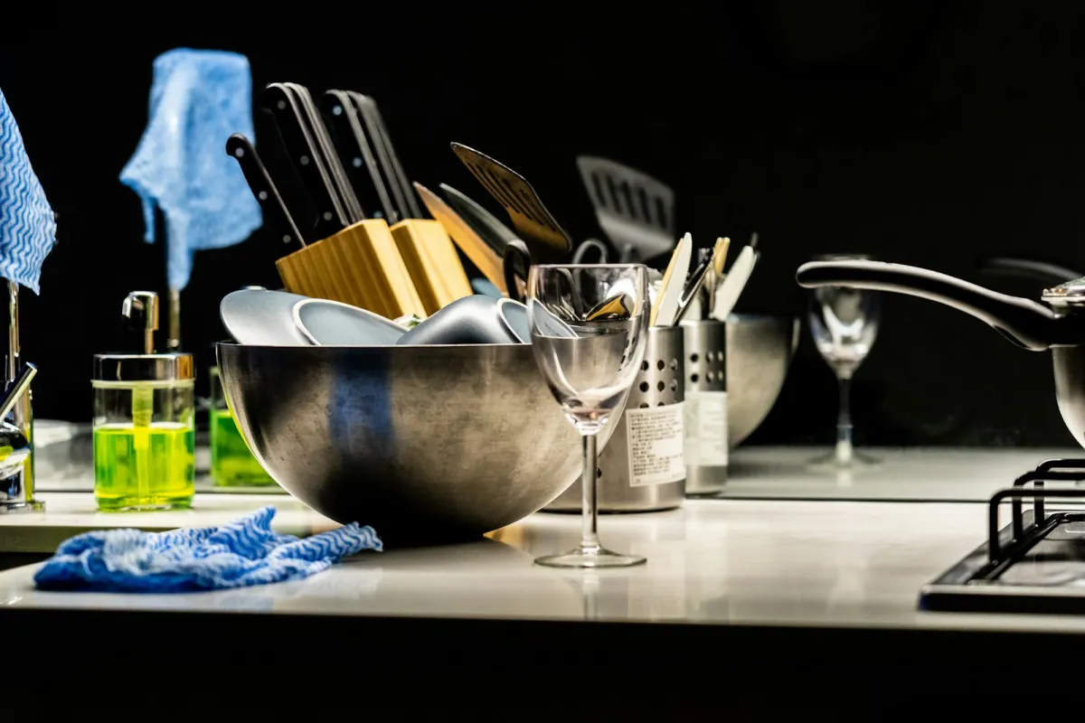 Washed bowls, glasses and utensils drying on a kitchen worktop beside cleaning cloths Washed bowls, glasses and utensils drying on a kitchen worktop beside cleaning cloths