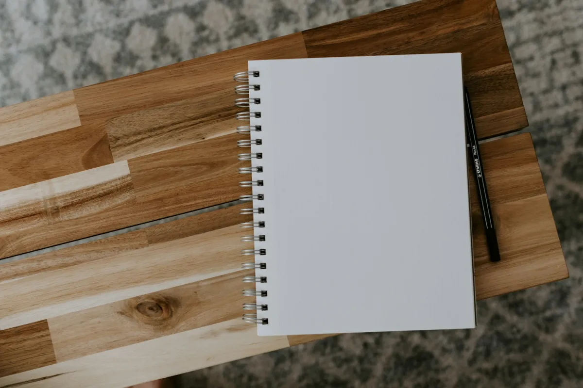 A white spiral notebook on a wooden table