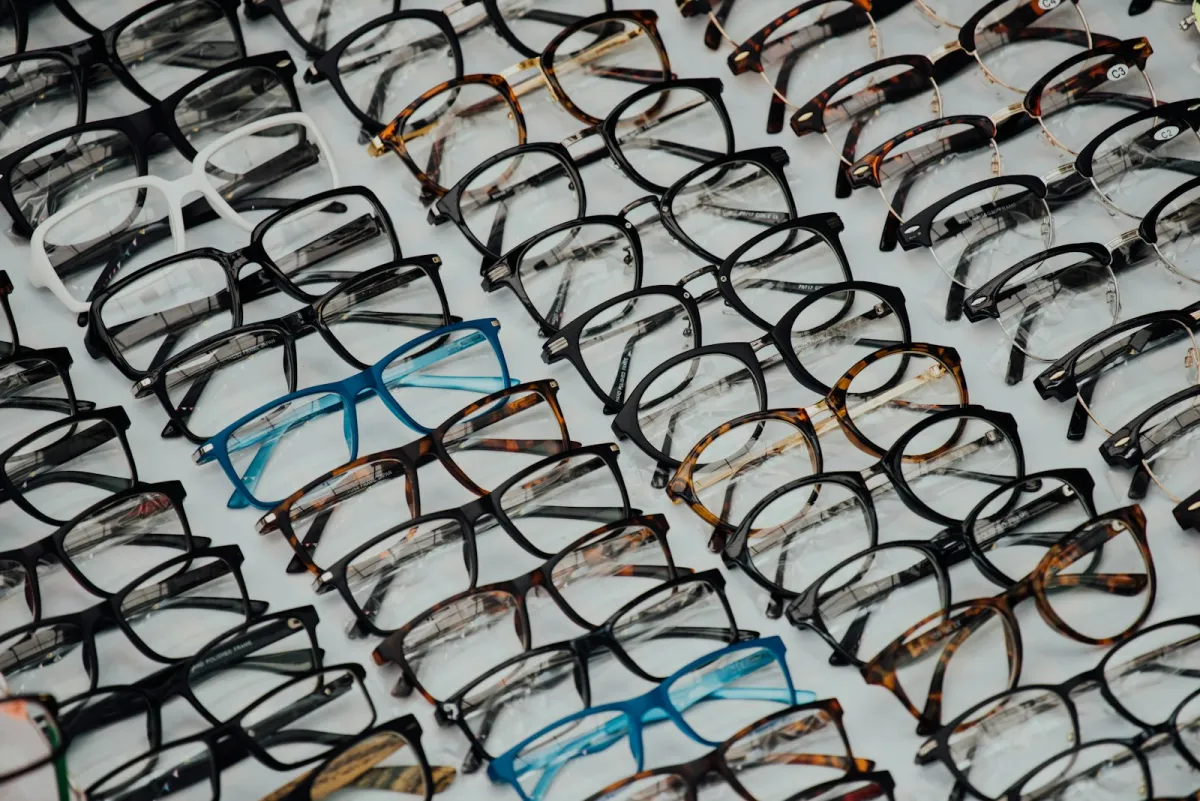 Rows of black, tortoiseshell and blue glasses frames laid out on a table