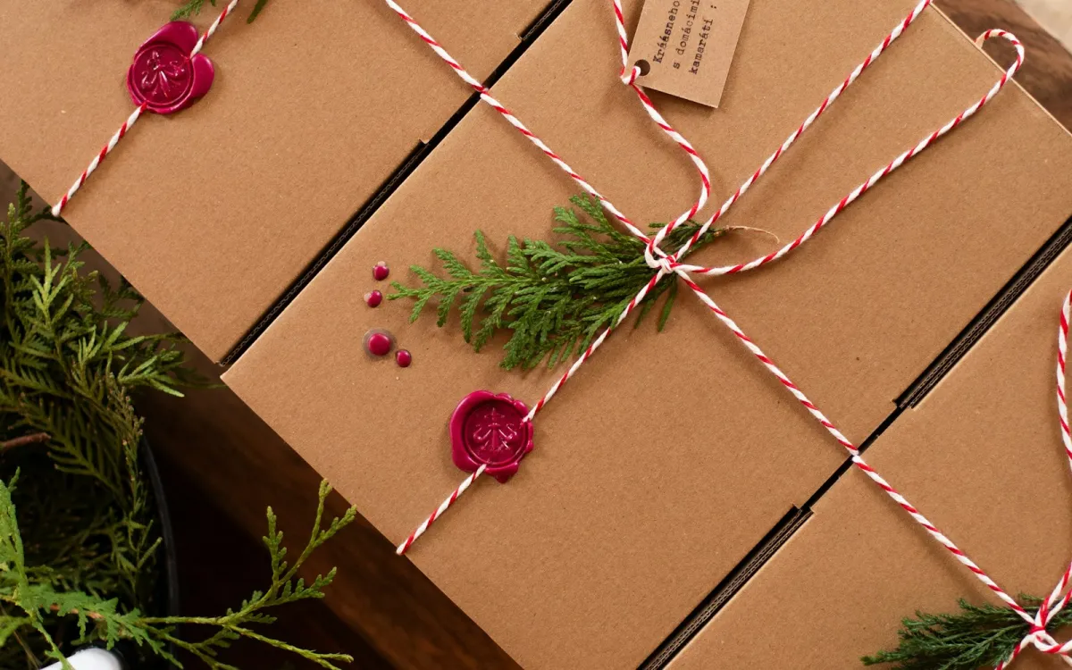 Brown gift boxes tied with red and white string, sealed with red wax and sprigs of greenery Brown gift boxes tied with red and white string, sealed with red wax and sprigs of greenery