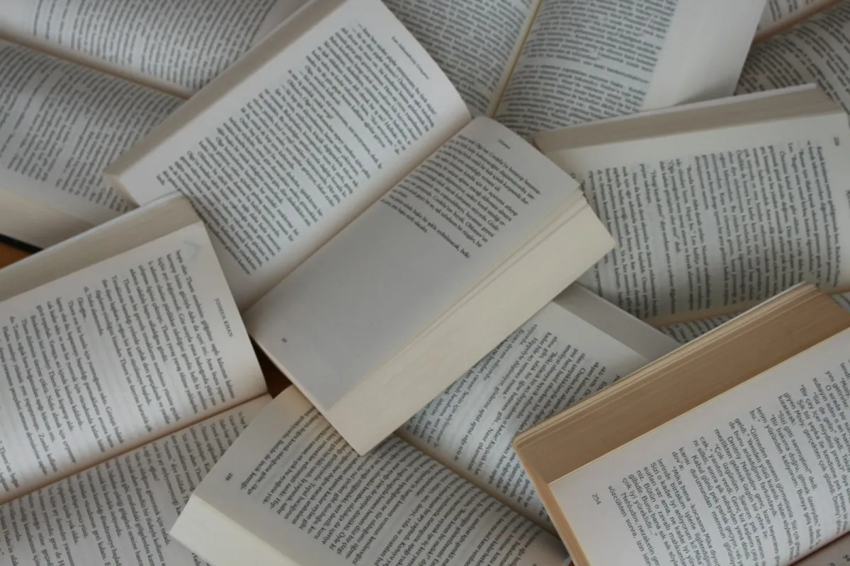 A jumble of open paperback books lying on top of one another A jumble of open paperback books lying on top of one another