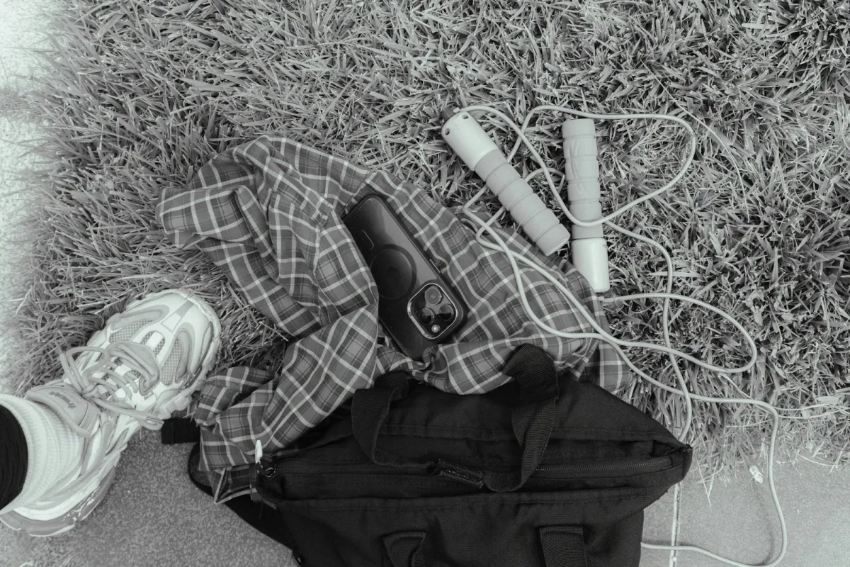Workout gear including a skipping rope, gym bag and trainers laid out on grass