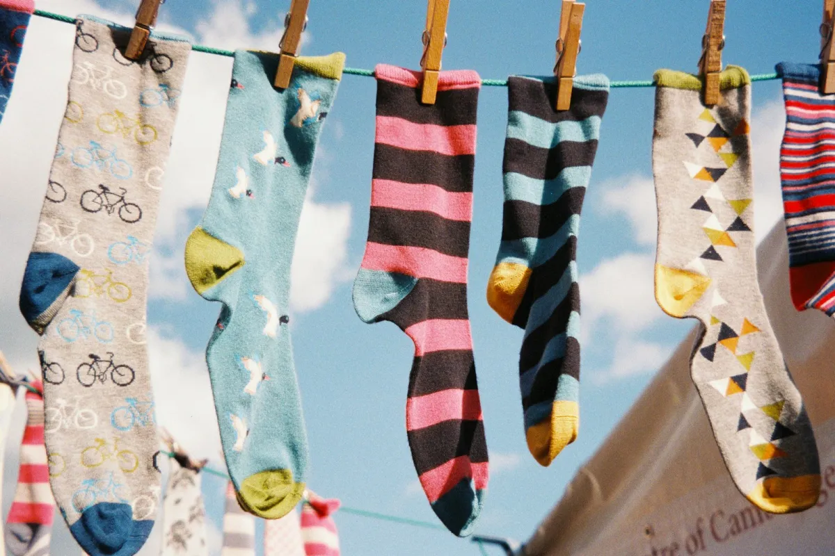 Colourful patterned socks with bikes, birds and stripes pegged on a washing line against a blue sky Colourful patterned socks with bikes, birds and stripes pegged on a washing line against a blue sky