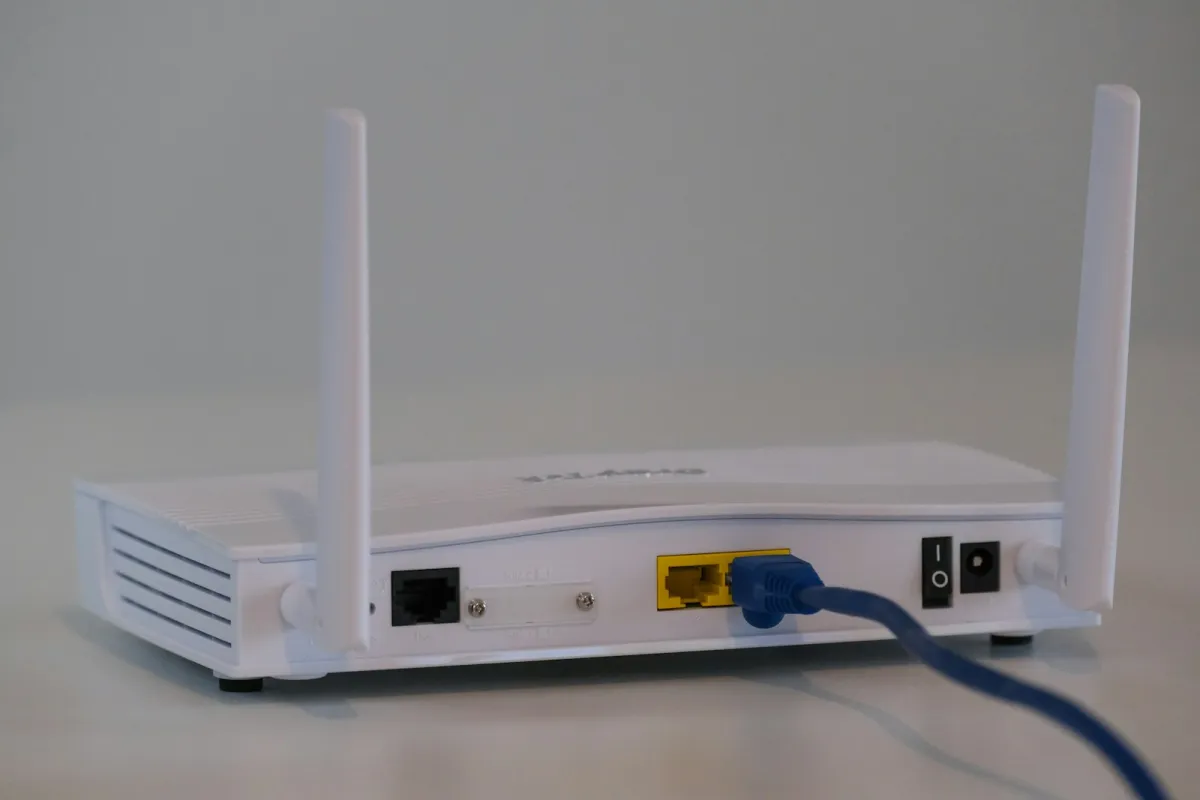 Back of a white broadband router with a blue network cable plugged in