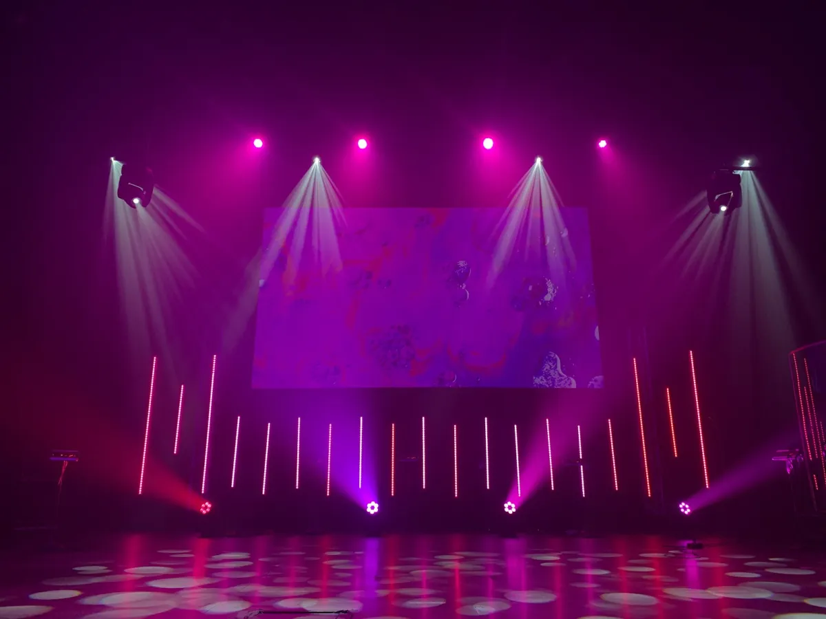 Empty stage lit by pink and white spotlights and LED bars