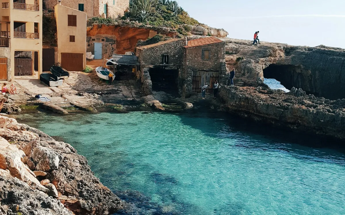 Clear turquoise water in the rocky cove of Cala S'Almunia, Mallorca, with old stone boathouses Clear turquoise water in the rocky cove of Cala S'Almunia, Mallorca, with old stone boathouses