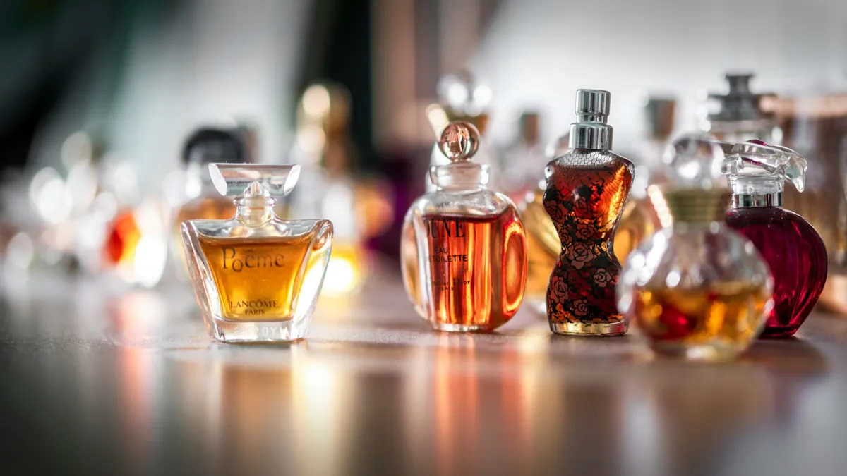 A row of glass perfume bottles in amber and red tones on a table