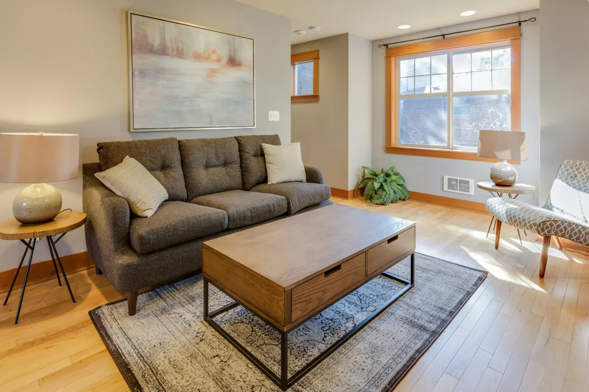 Bright living room with a grey sofa, cushions, wooden coffee table, rug and table lamps Bright living room with a grey sofa, cushions, wooden coffee table, rug and table lamps