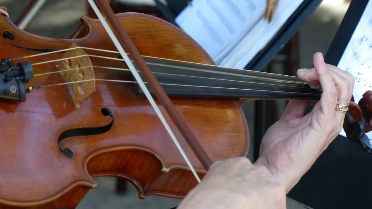 Close-up of hands playing a violin in front of a music stand