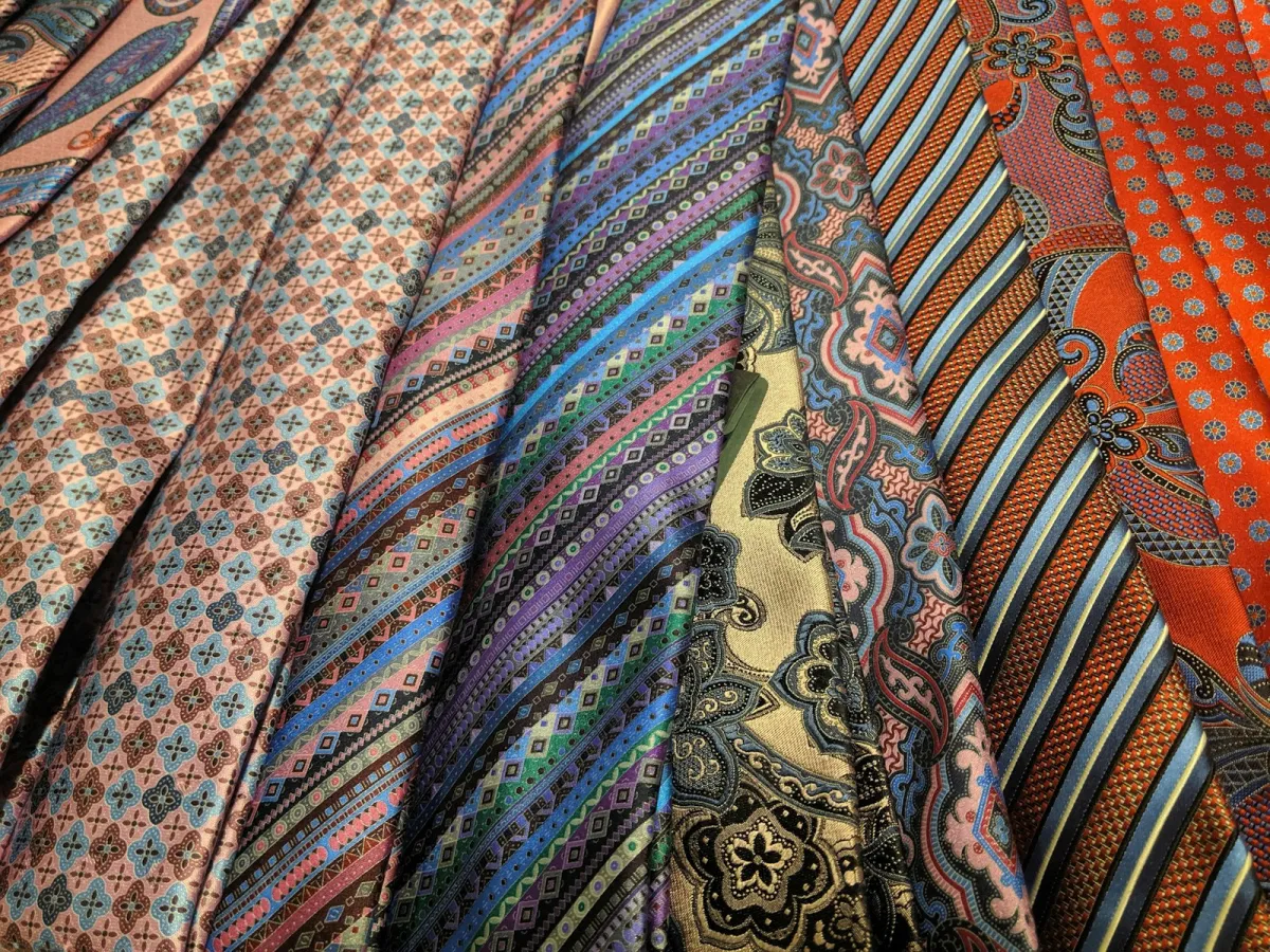 A row of colourful patterned silk ties laid side by side A row of colourful patterned silk ties laid side by side