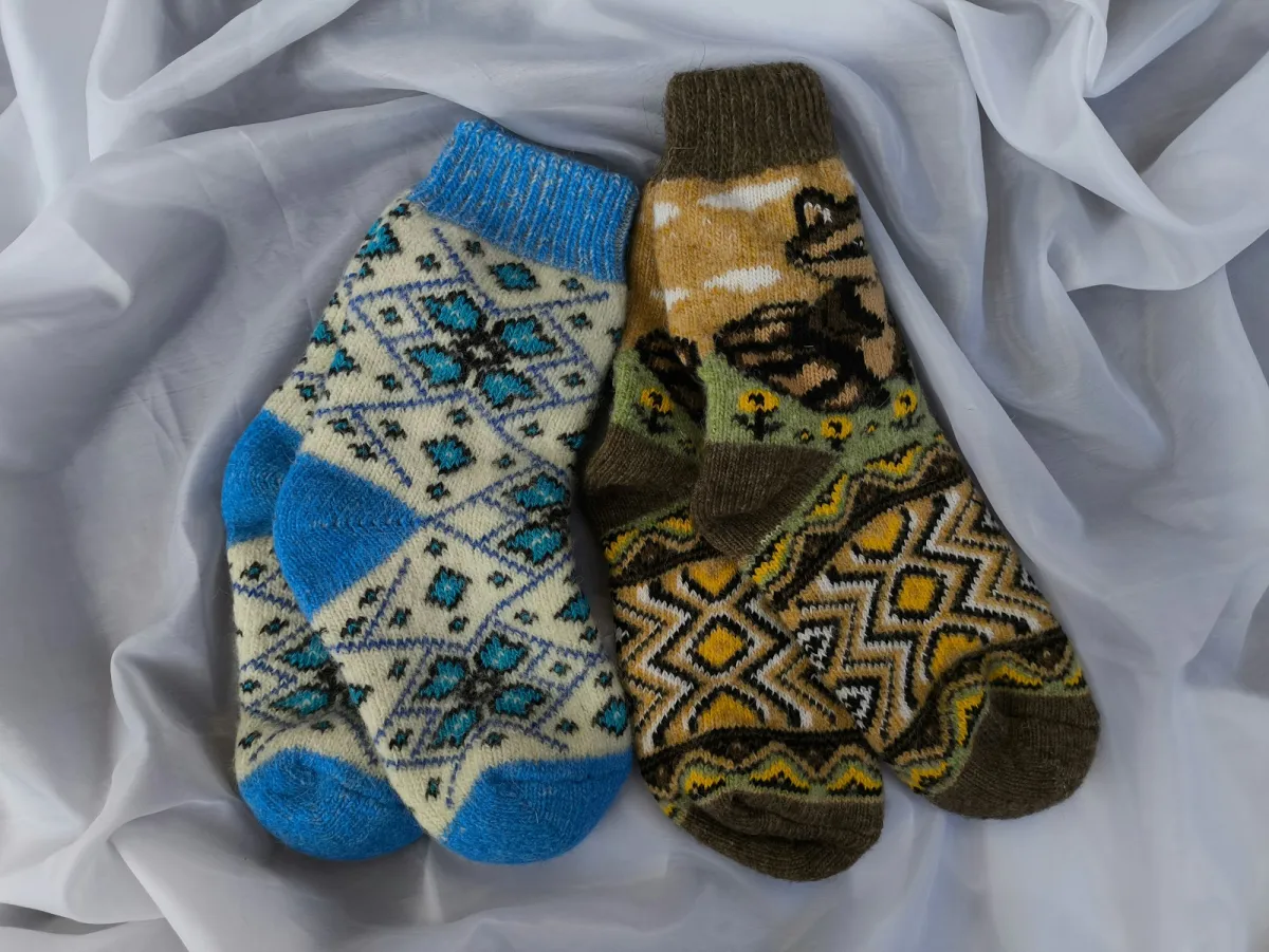 Two pairs of patterned wool socks laid on a white sheet