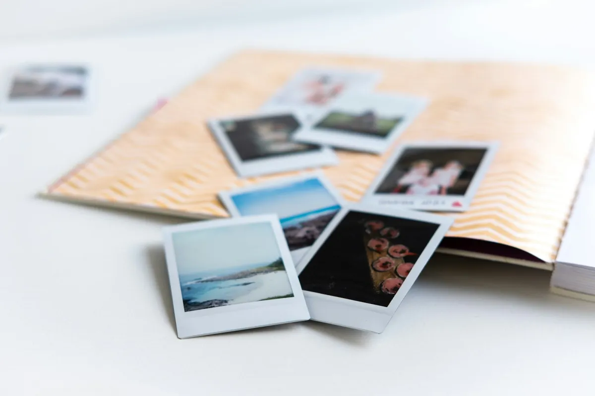 Instant photo prints scattered over an open photo album Instant photo prints scattered over an open photo album