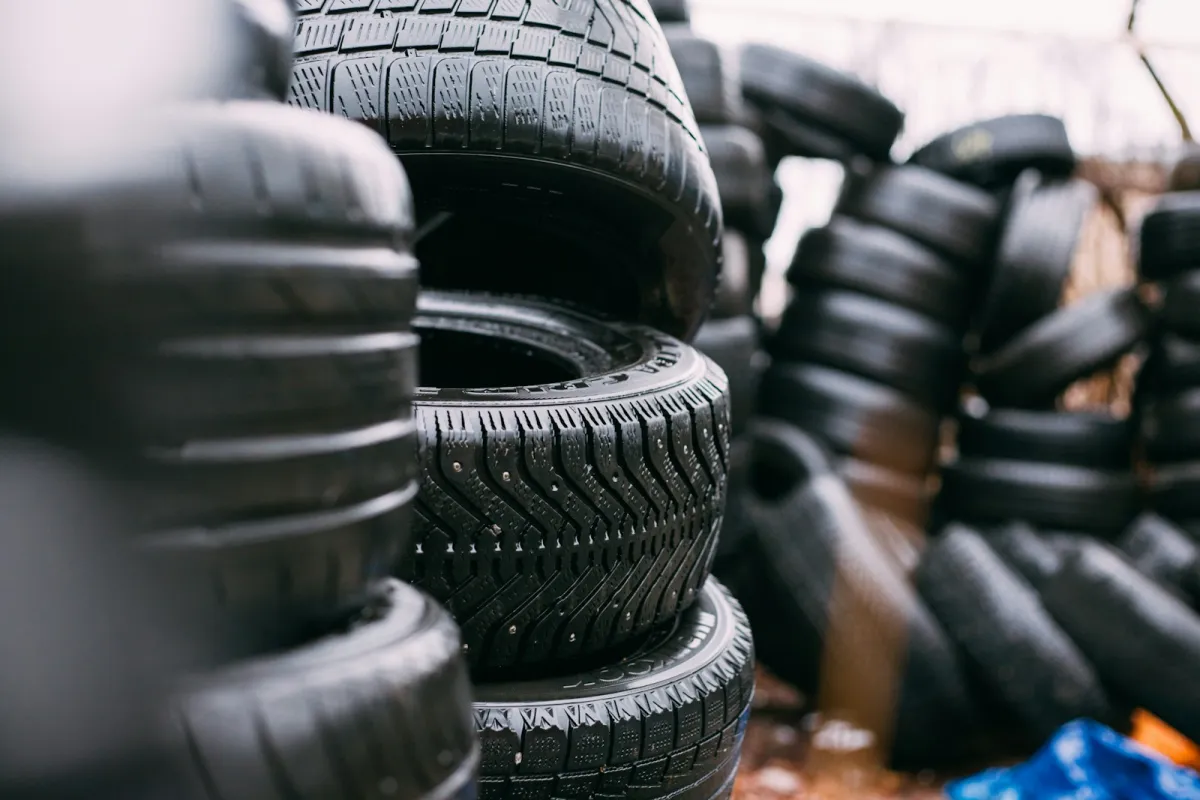 Stacks of car tyres with deep winter tread, piled up outdoors