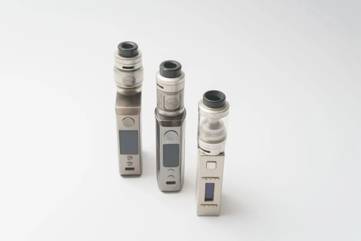 Three metal box-mod vape kits with tanks standing on a white background Three metal box-mod vape kits with tanks standing on a white background
