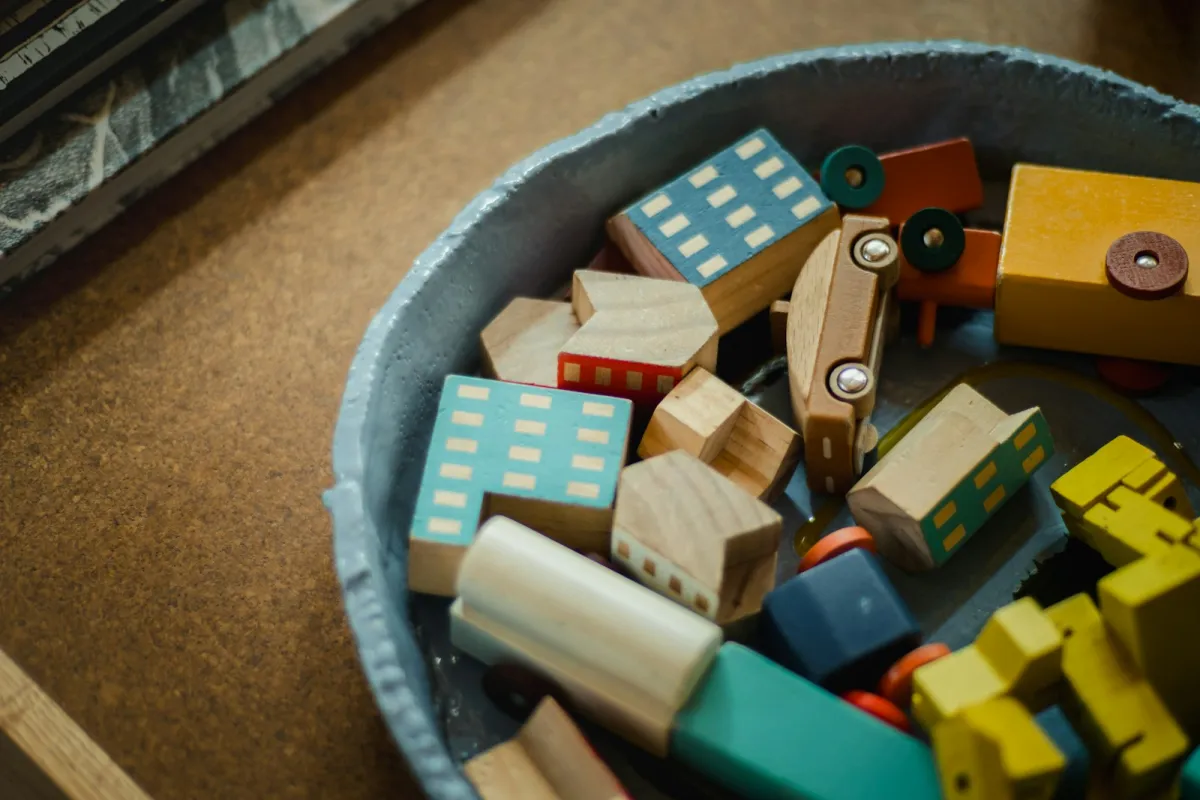 A bowl of colourful wooden toy blocks, houses and vehicles A bowl of colourful wooden toy blocks, houses and vehicles